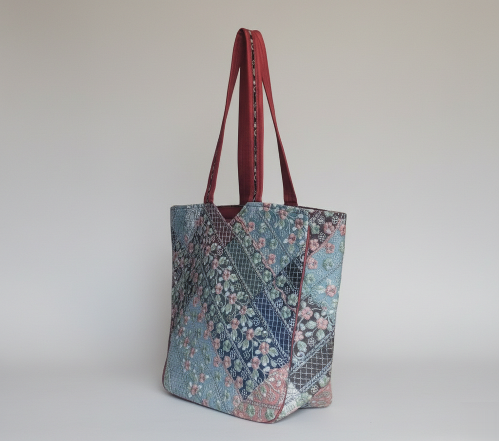 Close-up of Ahir embroidery floral stitching detail on red tote